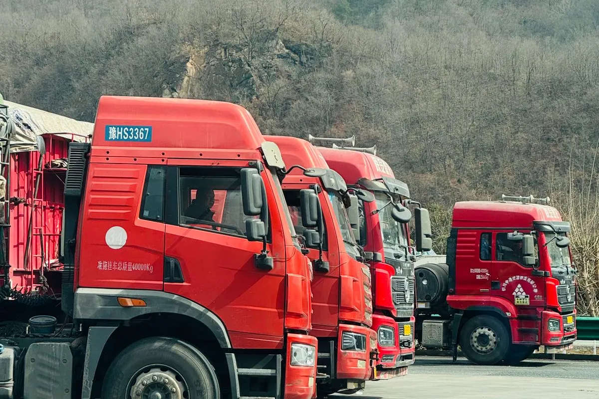 Row of red closed-body trucks in a yard